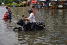 a man riding a motorcycle through a flooded street