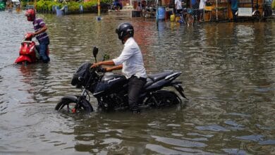 a man riding a motorcycle through a flooded street